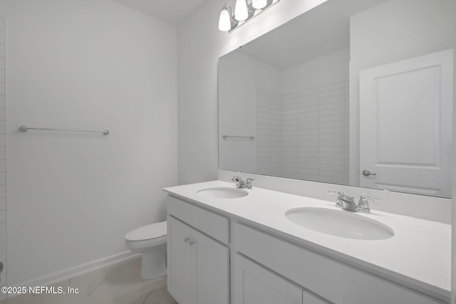 full bathroom with toilet, marble finish floor, double vanity, and a sink