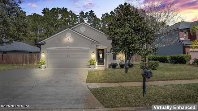 view of front of house featuring an attached garage, fence, driveway, stucco siding, and a front lawn