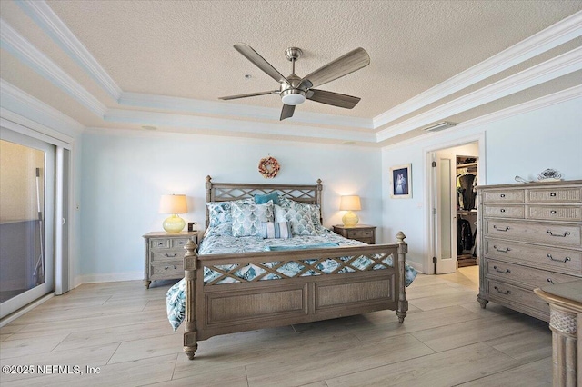 bedroom with a textured ceiling, light wood-type flooring, a raised ceiling, and visible vents