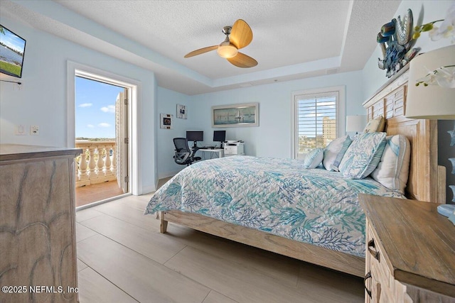 bedroom featuring ceiling fan, a tray ceiling, and a textured ceiling