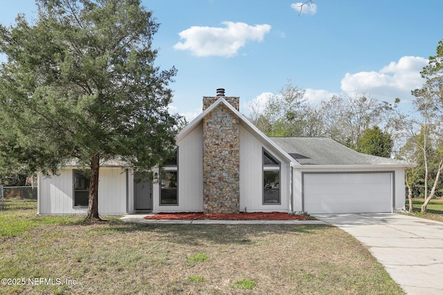 mid-century home featuring a chimney, a shingled roof, a front yard, a garage, and driveway