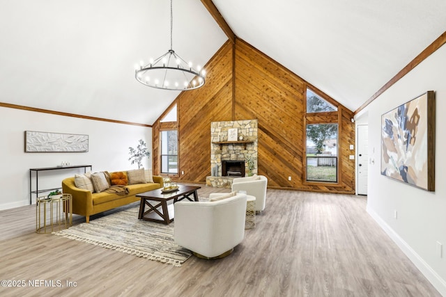 living room with a notable chandelier, a fireplace, wood walls, wood finished floors, and high vaulted ceiling