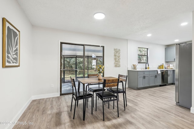 dining space featuring a textured ceiling, recessed lighting, light wood-type flooring, and baseboards