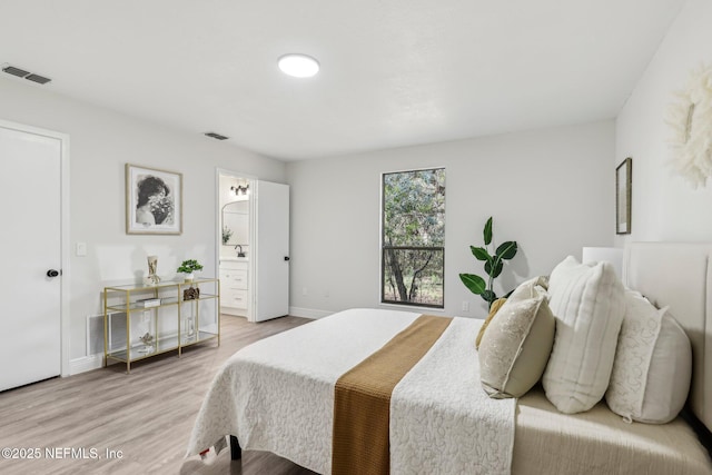 bedroom featuring connected bathroom, wood finished floors, visible vents, and baseboards