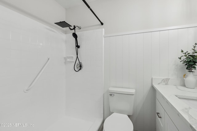 bathroom featuring toilet, a tile shower, and vanity