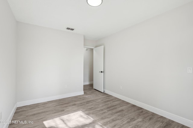 empty room with light wood-type flooring, visible vents, and baseboards