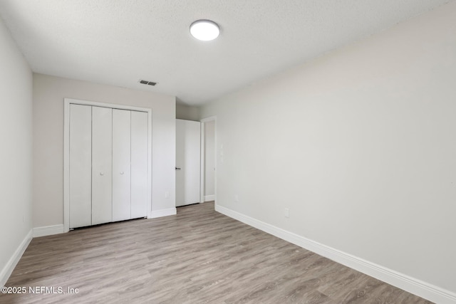 unfurnished bedroom with visible vents, light wood-style flooring, and baseboards