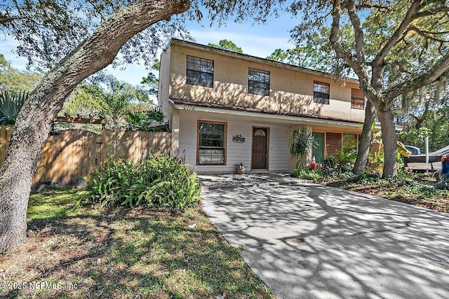 view of front of house featuring driveway, a porch, and fence