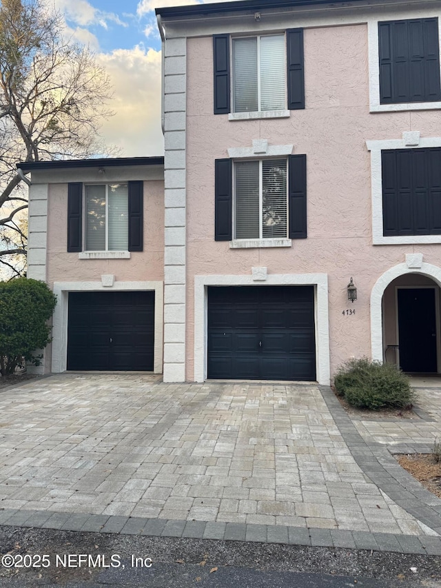 view of front facade featuring a garage, decorative driveway, and stucco siding