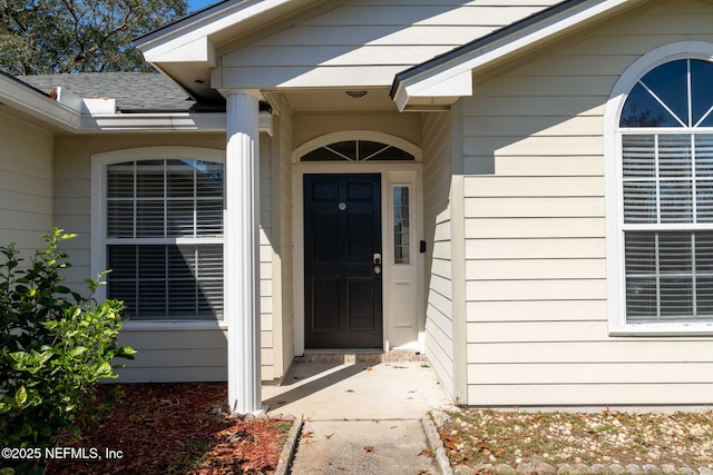 view of exterior entry featuring roof with shingles