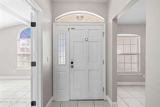 entryway featuring light tile patterned floors, baseboards, and a textured ceiling