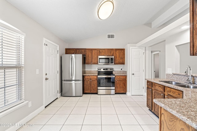 kitchen featuring stainless steel appliances, lofted ceiling, visible vents, light tile patterned flooring, and a sink