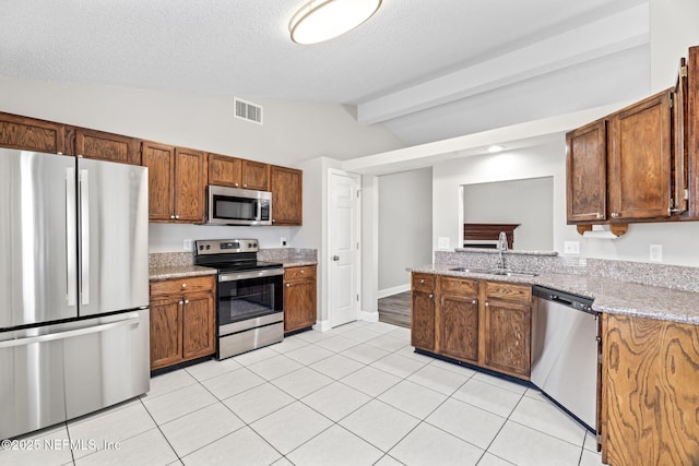 kitchen with vaulted ceiling with beams, light tile patterned floors, a sink, visible vents, and appliances with stainless steel finishes