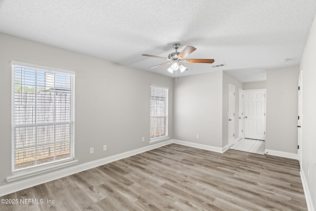 unfurnished room featuring ceiling fan, wood finished floors, visible vents, and baseboards