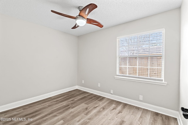 spare room featuring ceiling fan, a textured ceiling, baseboards, and wood finished floors