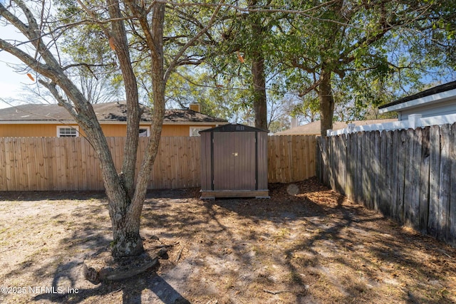 view of yard with a fenced backyard, an outdoor structure, and a storage shed