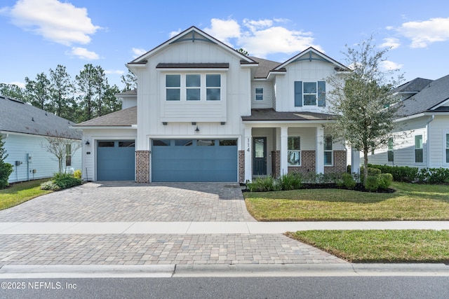 craftsman-style house with a garage, brick siding, decorative driveway, board and batten siding, and a front yard