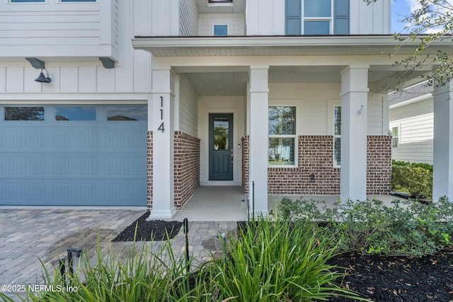 entrance to property with covered porch, board and batten siding, and brick siding