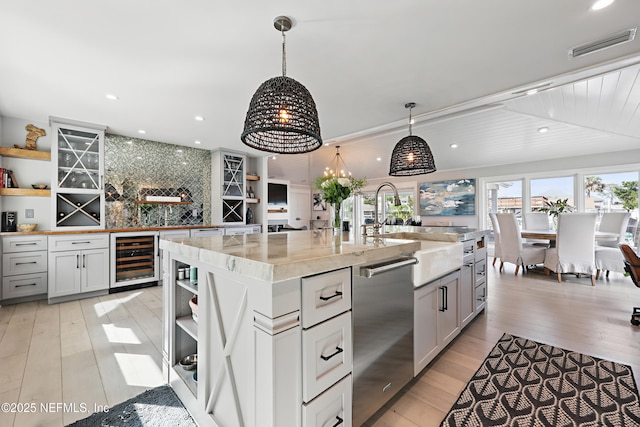 kitchen with pendant lighting, visible vents, an island with sink, and open shelves