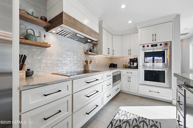 kitchen featuring open shelves, tasteful backsplash, appliances with stainless steel finishes, white cabinets, and premium range hood