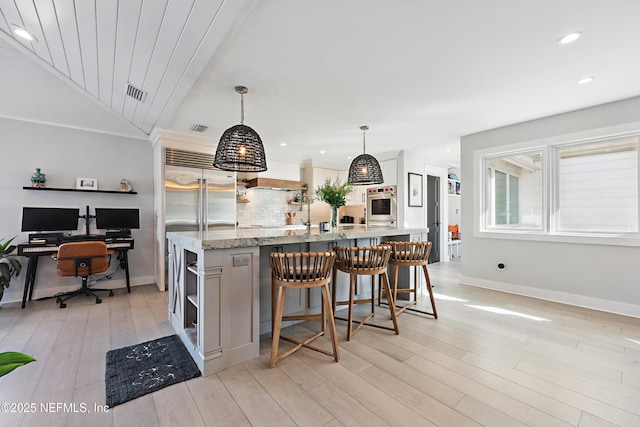 kitchen with open shelves, light stone counters, stainless steel appliances, and decorative light fixtures