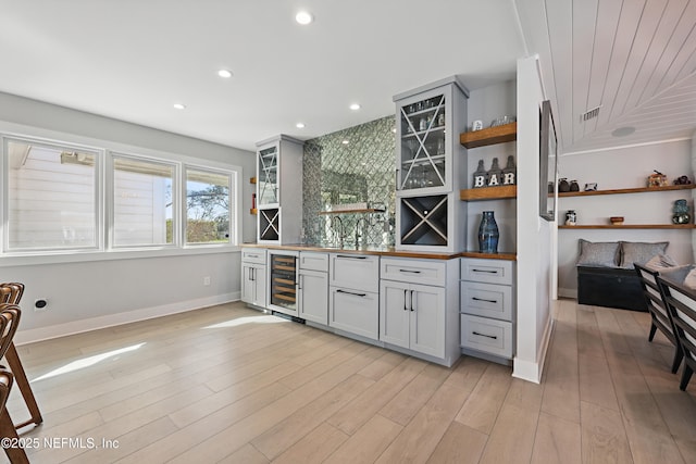 bar with recessed lighting, beverage cooler, light wood-style floors, baseboards, and wet bar