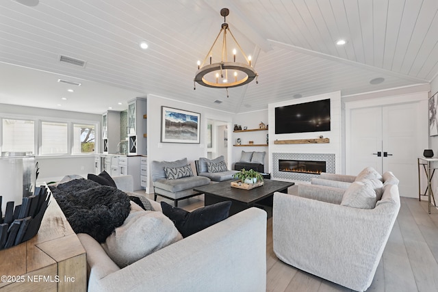 living room featuring light wood finished floors, visible vents, a glass covered fireplace, wood ceiling, and vaulted ceiling