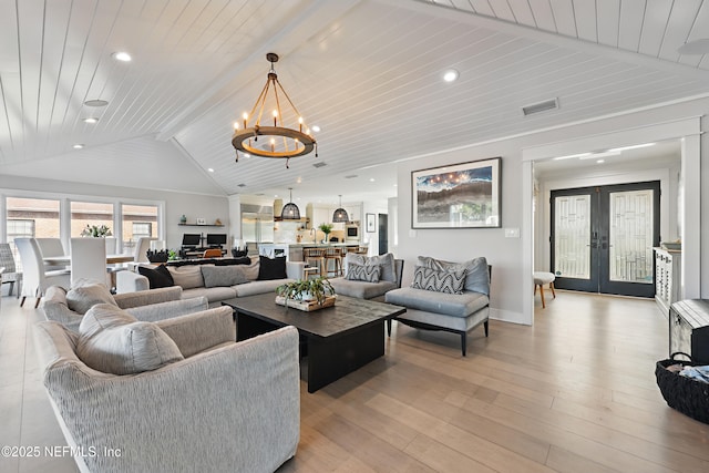 living area featuring lofted ceiling with beams, french doors, visible vents, and light wood-style floors