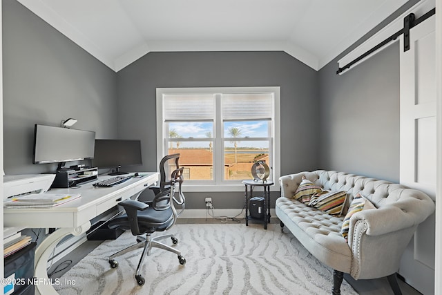 office space with vaulted ceiling, baseboards, and a barn door