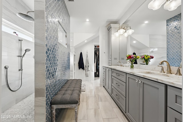 bathroom featuring double vanity, walk in shower, a walk in closet, and a sink