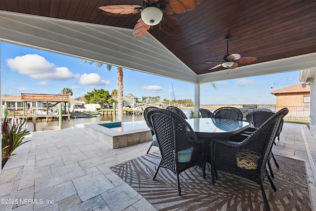 view of patio / terrace featuring a water view, ceiling fan, a hot tub, and outdoor dining space