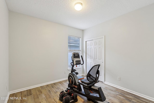 workout room with a textured ceiling, wood finished floors, and baseboards