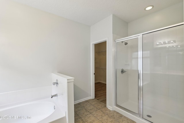 full bathroom featuring a walk in closet, a garden tub, a shower stall, and tile patterned floors