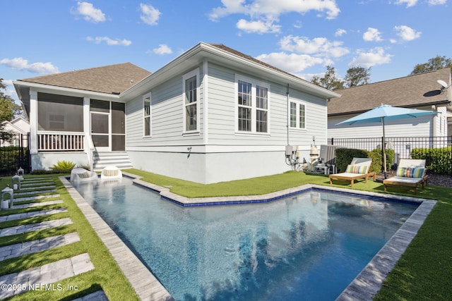 rear view of house featuring a fenced in pool, a lawn, entry steps, a sunroom, and fence