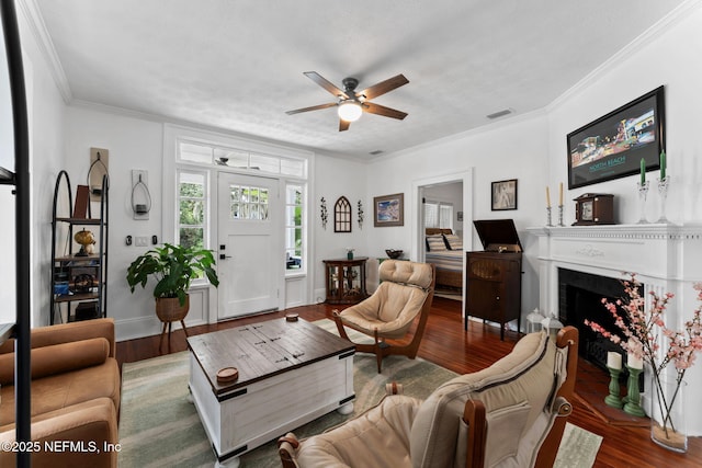 living area featuring ornamental molding, visible vents, a fireplace, and wood finished floors