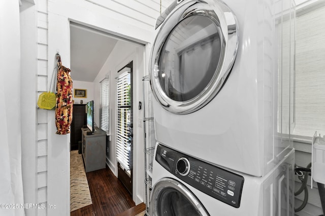 clothes washing area with dark wood-style floors, stacked washer and clothes dryer, and laundry area