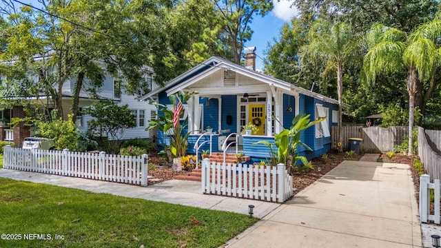 bungalow-style house featuring covered porch, a fenced front yard, and a chimney