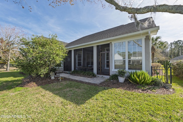 exterior space featuring a shingled roof, fence, a front lawn, and a sunroom