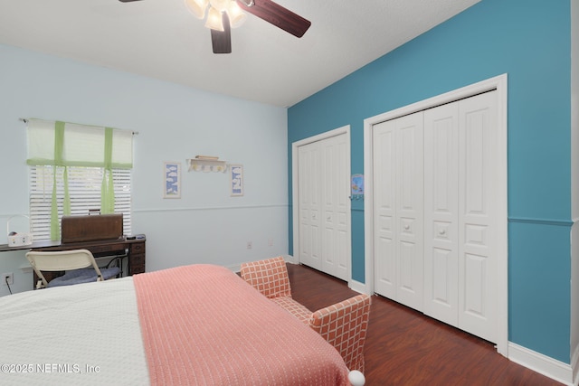 bedroom with baseboards, two closets, wood finished floors, and a ceiling fan