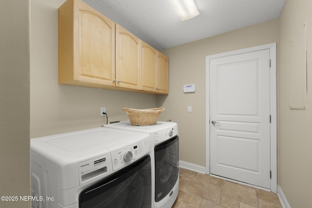 clothes washing area featuring stone finish flooring, a textured ceiling, cabinet space, separate washer and dryer, and baseboards