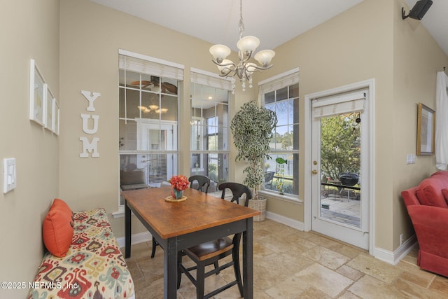 dining room with a chandelier, stone tile floors, and baseboards