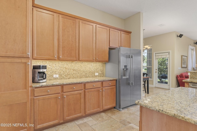 kitchen featuring decorative backsplash, light stone countertops, brown cabinets, and high end refrigerator