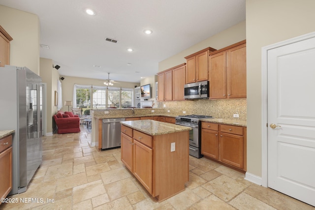 kitchen featuring a peninsula, stone tile floors, visible vents, and stainless steel appliances