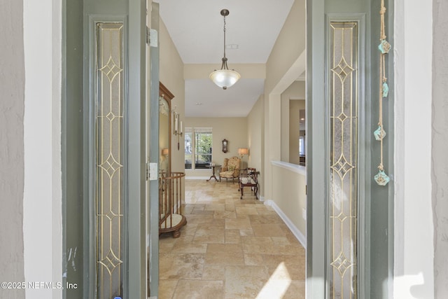 foyer entrance with baseboards and stone tile flooring