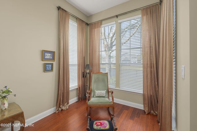 living area with baseboards and wood finished floors