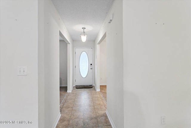 doorway featuring baseboards and a textured ceiling