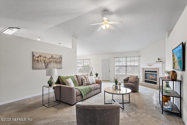 living area with a textured ceiling, a tile fireplace, baseboards, vaulted ceiling, and carpet