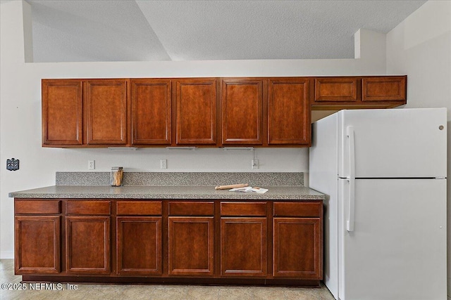 kitchen with a textured ceiling, dark countertops, and freestanding refrigerator