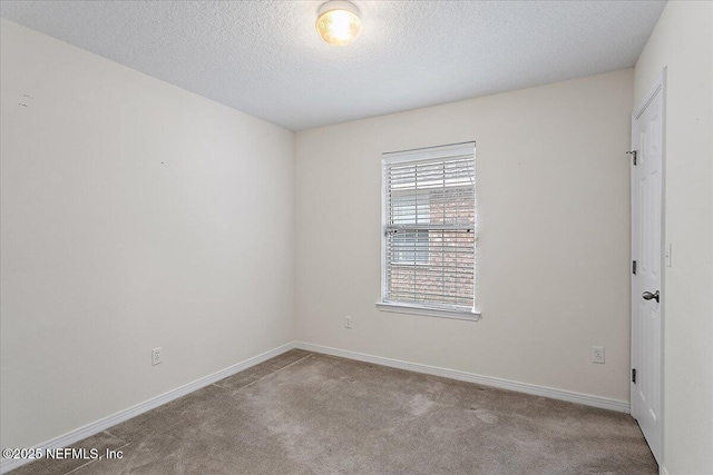 carpeted empty room with a textured ceiling and baseboards