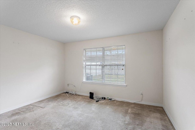 unfurnished room with a textured ceiling, carpet flooring, and baseboards